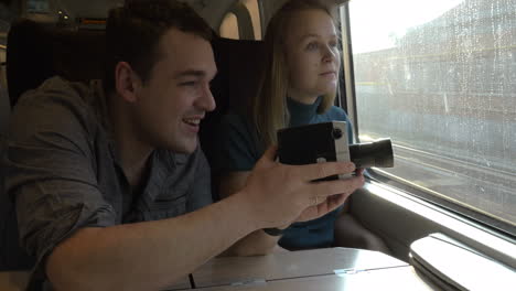 Young-couple-with-retro-video-camera-in-train