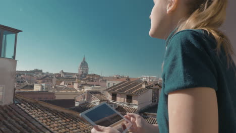 Woman-using-pad-on-the-balcony-with-city-view