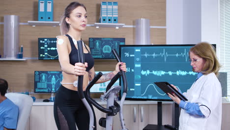 Female-athlete-runs-on-treadmill-with-electrodes-attrached-on-her-body