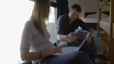 Man-and-woman-talking-while-using-pad-and-laptop