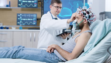 Doctor-holding-tablet-and-making-adjustments-on-brain-sensors-attrached-to-patient