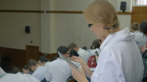Female-medical-student-with-pad-on-the-lecture