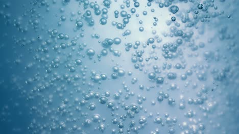 Many-water-bubbles-in-blue-water-close-up,-abstract-water-wave-with-bubbles-in-slow-motion.