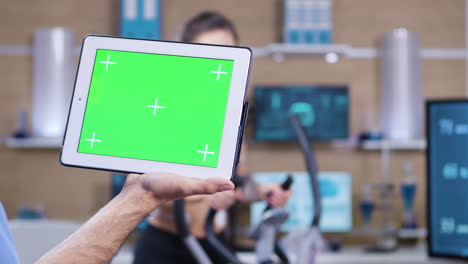 Dolly-shot-of-doctor-in-sport-science-holding-tablet-with-green-screen