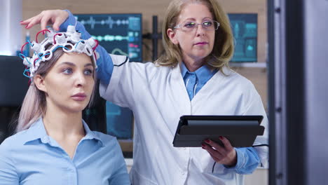 Dolly-shot-of-female-doctor-checking-the-sensors-from-patient-headset