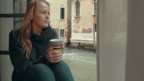 Wistful-woman-having-coffee-at-home-in-Venice