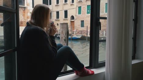 Woman-drinking-coffee-and-looking-at-Venice-view