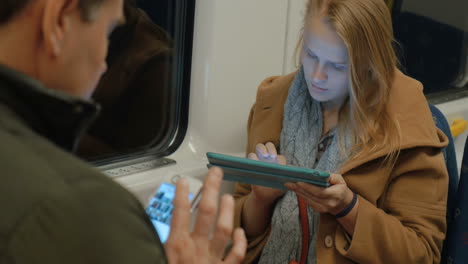 Woman-in-Metro-Train-Typing-in-Tablet