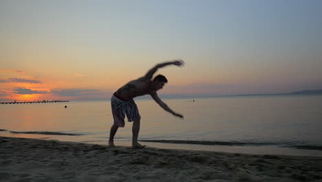 Man-showing-acrobatics-at-seaside-during-sunset