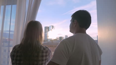 Young-couple-looking-at-big-city-through-the-window