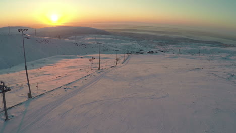 Ski-run-and-snowy-hills-at-sunset-aerial-view