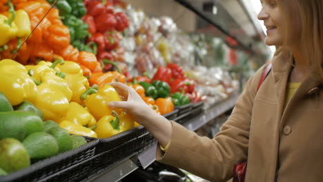 Glückliches-Mädchen,-Das-Frische-Gelbe-Paprika-Im-Lebensmittelgeschäft-Kauft