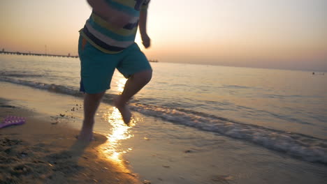 Child-running-barefoot-along-the-sea-at-sunset