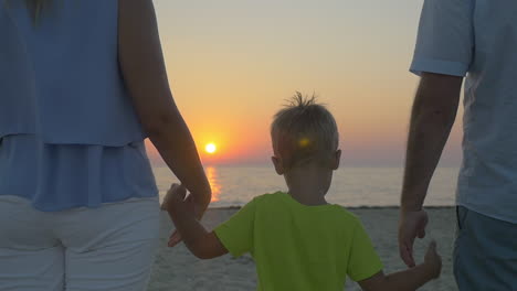 Family-with-child-looking-at-sunset-over-sea
