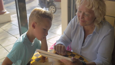 Grandmother-and-grandson-with-pad-in-cafe