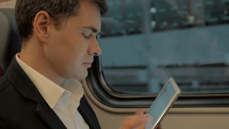 Young-businessman-chatting-on-pad-in-the-train
