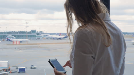 Woman-texting-on-cell-and-looking-at-airport-area