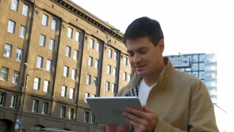 Mann-Benutzt-Tablet-Computer-Unterwegs-In-Der-Stadt