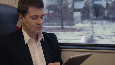 Young-businessman-working-with-pad-in-the-train