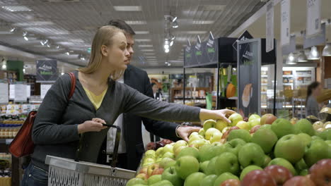 Young-people-choosing-apples-in-the-supermarket