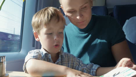 Son-and-mother-with-pictured-book-in-train
