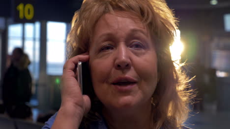 Senior-woman-having-a-vivid-phone-talk-at-airport