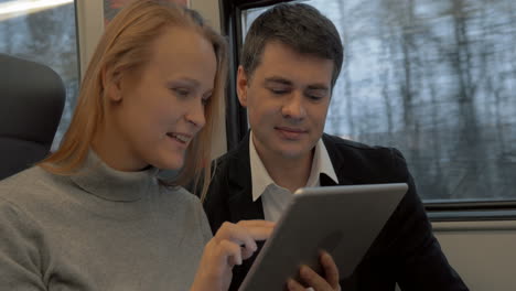 Young-people-working-with-pad-and-talking-in-the-train