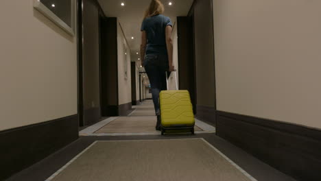 Frau-Mit-Koffer-Läuft-Im-Hotelkorridor