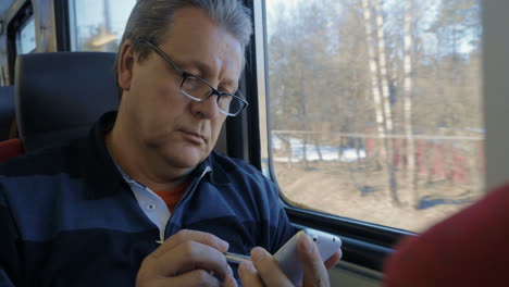 Senior-man-surfing-the-internet-on-cellphone-in-train