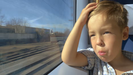 Kleiner-Junge-Schaut-An-Einem-Sonnigen-Tag-Aus-Dem-Zugfenster