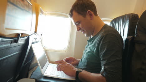 Young-man-chatting-on-laptop-in-the-plane