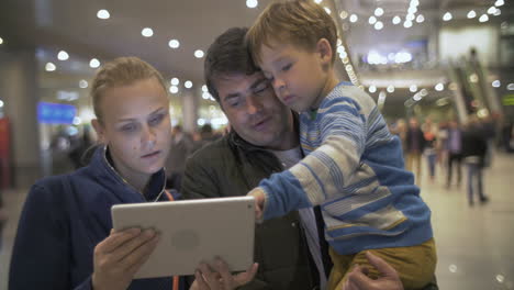 Parents-and-child-with-pad-at-the-crowded-airport