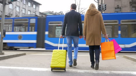 Couple-with-suitcase-and-shopping-bags-crossing-the-road