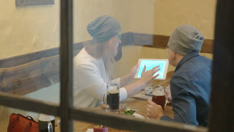Young-hipsters-drinking-beer-and-using-pad-in-cafe
