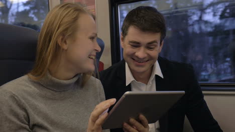 Friends-laughing-while-using-pad-in-train