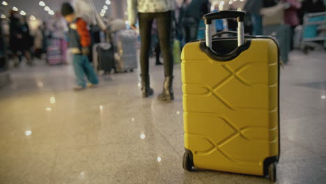 Gelber-Koffer-Auf-Dem-Boden-Am-überfüllten-Flughafen