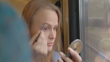 Woman-going-by-train-and-putting-on-make-up