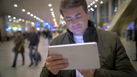 Mann-Mit-Tablet-PC-Im-Flughafen--Oder-Bahnterminal