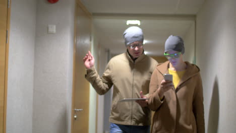 Hipster-friends-with-pad-and-cell-walking-in-hotel-hall