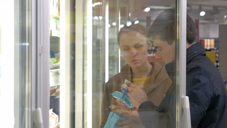 Young-family-couple-taking-products-in-fridge-section