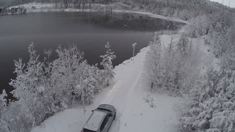 Car-getting-to-winter-recreation-through-pine-wood-aerial-view