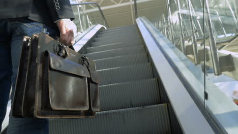 Businessman-with-leather-briefcase-riding-on-escalator