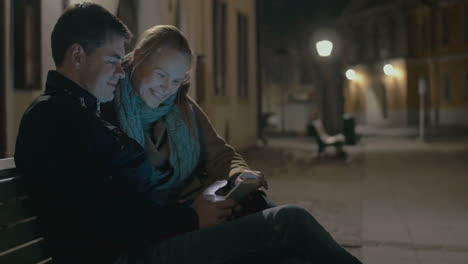 Young-couple-using-pad-on-the-street-bench