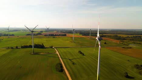 Luftaufnahme-Der-Windturbinen,-Die-In-Einem-Windpark-Arbeiten-Und-An-Einem-Sonnigen-Tag-Auf-Einer-Weiten-Grünen-Wiese-Grünen-Strom-Erzeugen,-Nutzung-Erneuerbarer-Energiequellen
