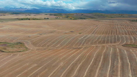Cinematic-drone-aerial-Grand-Targhee-Pass-Idaho-Grand-Tetons-National-Park-potato-wheat-farmland-dry-unique-crops-mountain-peak-landscape-backward-movement