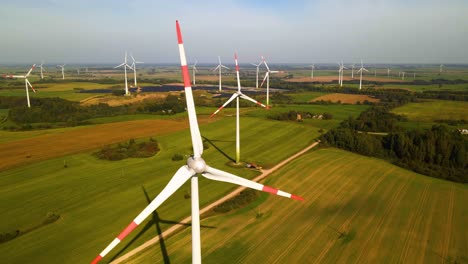 Aerial-footage-of-wind-turbines-in-a-wind-farm-generating-green-electric-energy-on-a-wide-green-field-on-a-sunny-day,-in-Taurage,-Lithuania