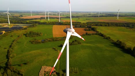 Luftaufnahme-Der-Windturbinen,-Die-In-Einem-Windpark-Arbeiten-Und-An-Einem-Sonnigen-Tag-Auf-Einer-Weiten-Grünen-Wiese-Grünen-Strom-Erzeugen,-Nutzung-Erneuerbarer-Energiequellen,-Parallaxe,-4k