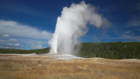 Cinematic-slide-famous-Old-Faithful-geyser-sunrise-sunset-eruption-Yellowstone-National-Park-observation-deck-viewing-area-Upper-Geyser-Basin-active-volcano-fall-autumn-beautiful-blue-sky-slow-motion
