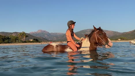 Teenage-redhead-girl-in-bikini-enjoying-a-refreshing-horseback-ride-in-summer-season