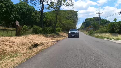 Nissan-X-Trail-Conduciendo-Por-La-Calle-Entre-árboles,-SUV-Crossover-Compacto,-Híbrido-De-Serie